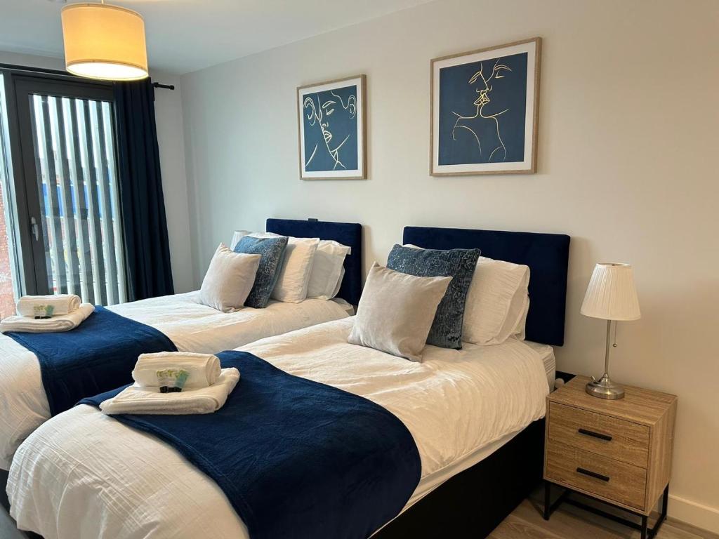 um quarto com 2 camas com lençóis azuis e brancos em 2 Bed 2 Bath in Digbeth em Birmingham