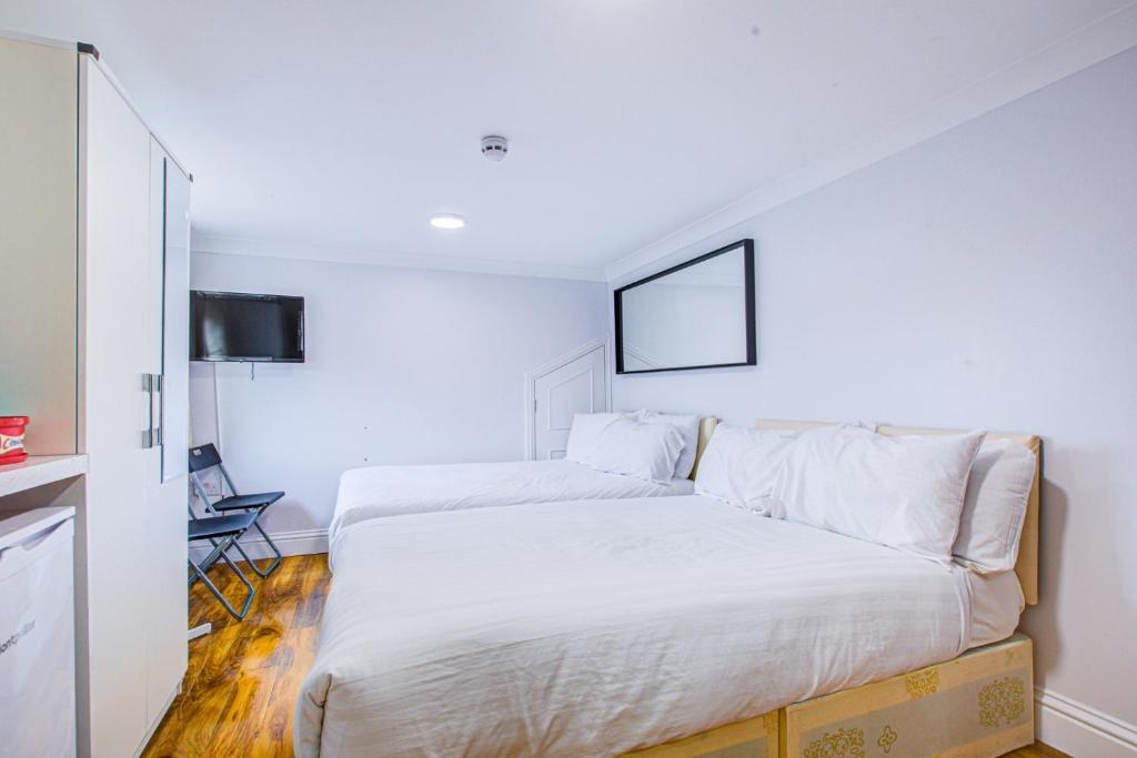 a bedroom with two beds and a tv on the wall at Streatley Apartments in London