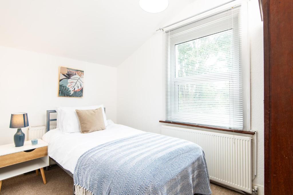 a white bedroom with a bed and a window at Single Room with a shared Kitchen and bathroom in a 5-Bedroom House at Hanwell in Hanwell