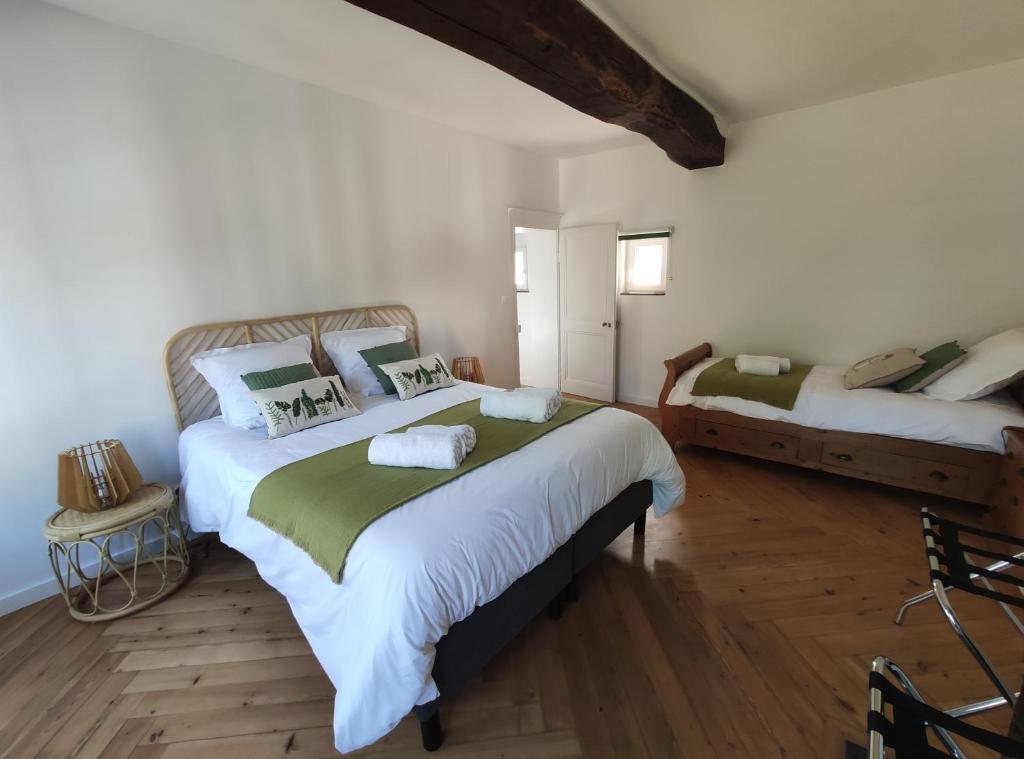 two beds in a room with white walls and wooden floors at Gîte de l'église à Saint Saëns in Saint-Saëns