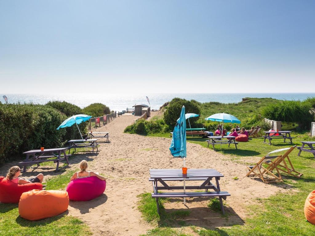 a group of people sitting on the beach with umbrellas at Beach House B&B in Bude