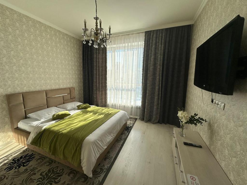 a bedroom with a bed and a flat screen tv at PROMENADE EXPO in Prigorodnyy