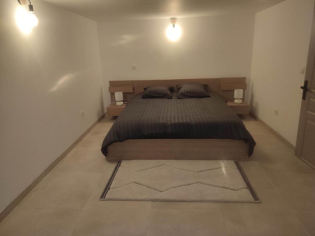 1 dormitorio con 1 cama con 2 lámparas y 1 alfombra en LES JARDINS D'ORANGE, en Orange