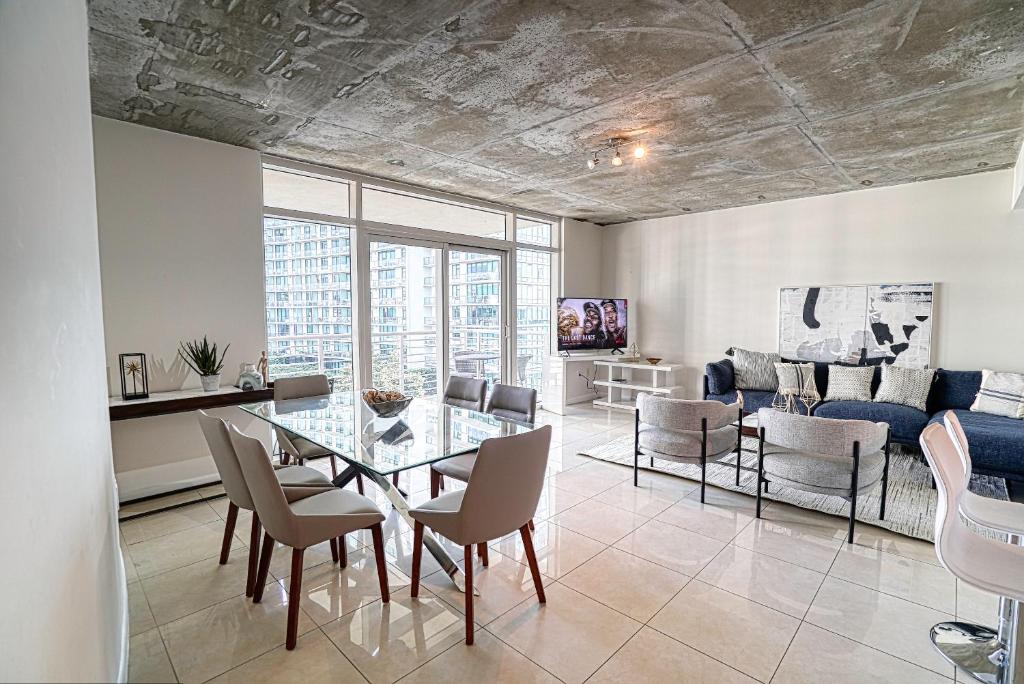 uma sala de estar com uma mesa de vidro e cadeiras em Prime Location: Midtown Miami Finest Condo em Miami