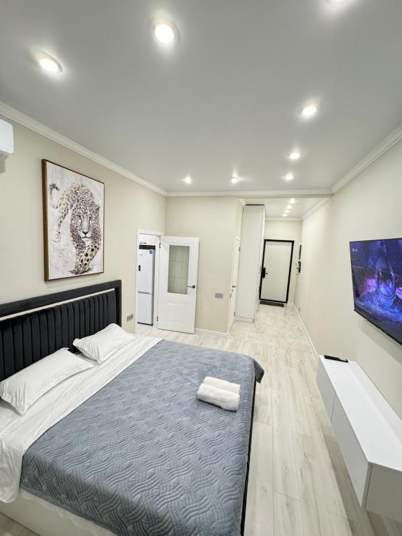 um quarto com uma cama grande e uma televisão em Жк DIAL RESIDENCE возле Арбата и Мега центра em Almaty
