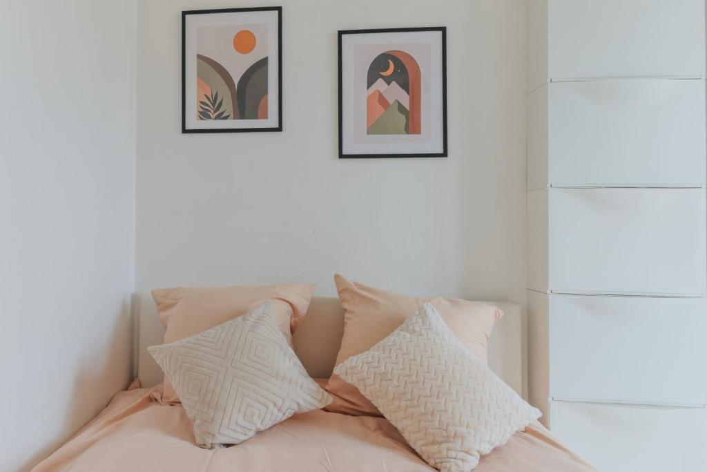 ein Bett mit vier Kissen und zwei Bildern an der Wand in der Unterkunft Bel appartement tout équipé de 24m2, proche Paris in Nanterre