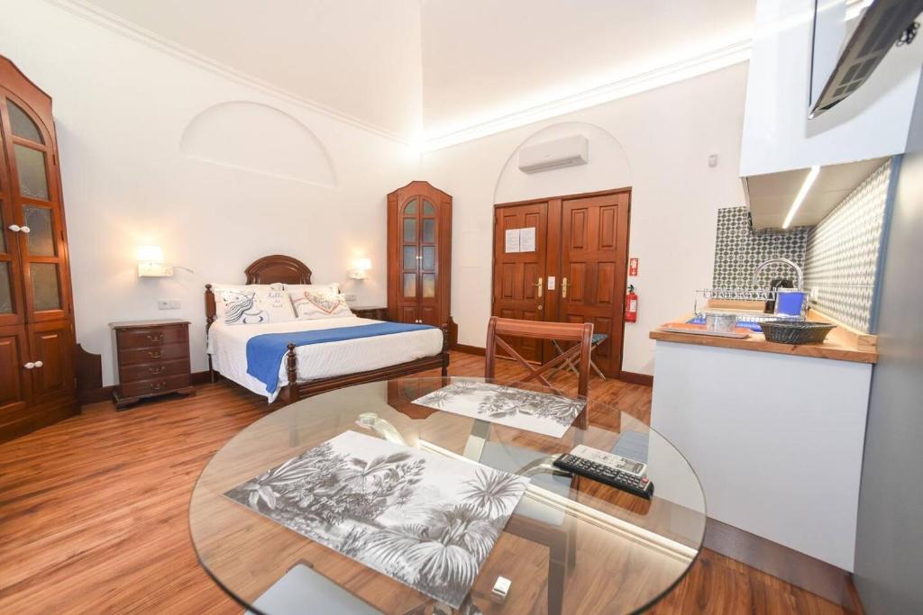 1 dormitorio con cama y mesa de cristal en One bedroom house with shared pool terrace and wifi at Canico 1 km away from the beach, en Caniço