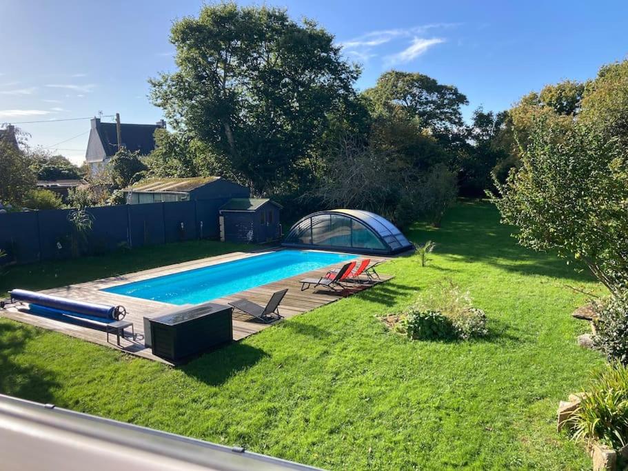 une cour avec une piscine sur gazon dans l'établissement Le gîte Marie-Galante : Belle maison d'hôtes avec accès piscine en été, à Lanmeur