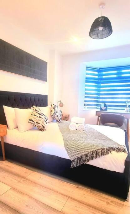 een slaapkamer met een groot bed met witte lakens en kussens bij Watford Gem Private Garden Mins to Harry Potter Studio in Watford