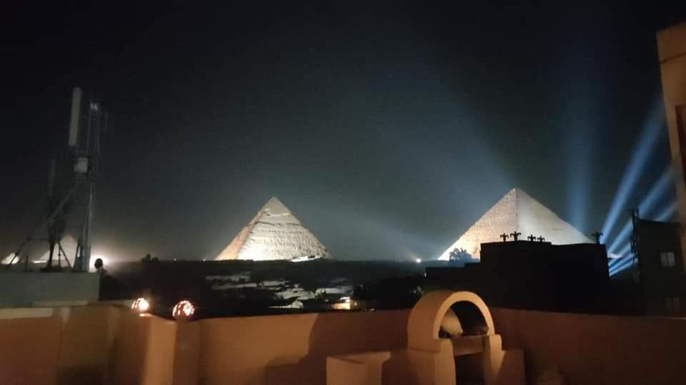 dos pirámides se iluminan por la noche con luces en New Tut pyramids hotel, en El Cairo