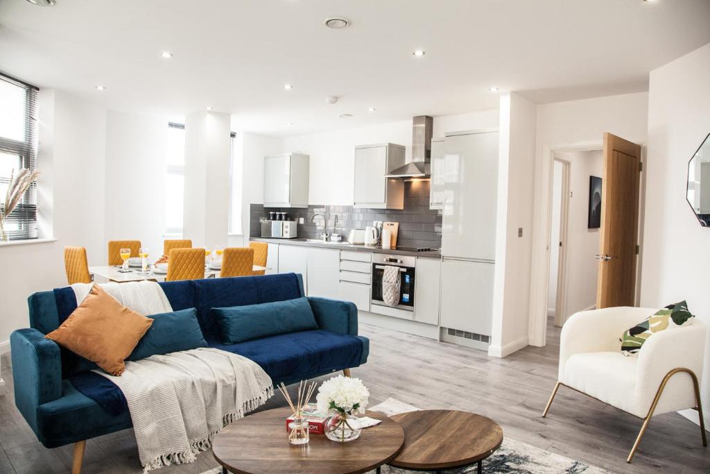 a living room with a blue couch and a kitchen at Cityscape 2-BR - Leicester's Premier Urban Retreat in Leicester