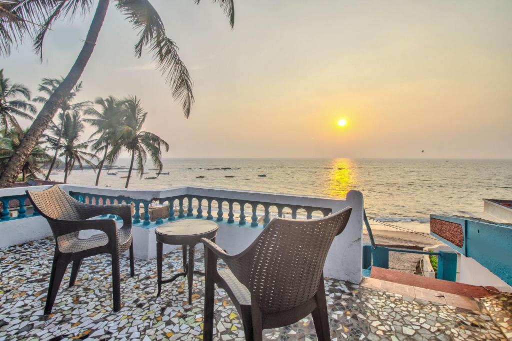 Villa Seafront Goa في أنجونا: طاولة وكراسي على شرفة مطلة على المحيط