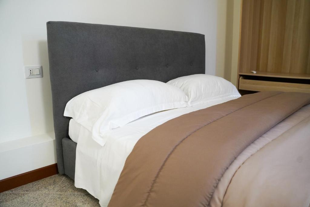 uma cama com lençóis brancos e almofadas num quarto em Boccadoro Rooms em San Zeno