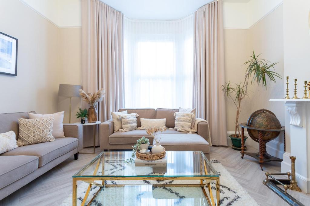uma sala de estar com um sofá e uma mesa de vidro em Stunning Large 4 Bedroom Victorian Home London em Londres