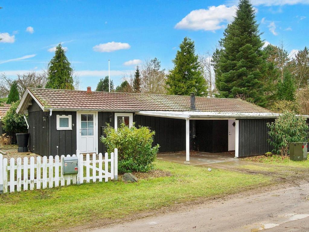 uma pequena casa preta com uma cerca branca em Holiday home Gørlev IV em Gørlev