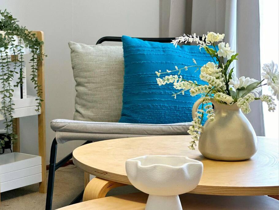 - une table avec un vase de fleurs et un oreiller bleu dans l'établissement 3 Bedroom Holiday Townhouse @ Belconnen, à Belconnen