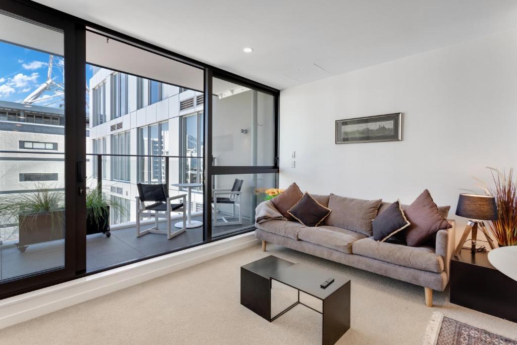 a living room with a couch and a large window at The CityScape Apartment with Wi-Fi and Balcony in Auckland
