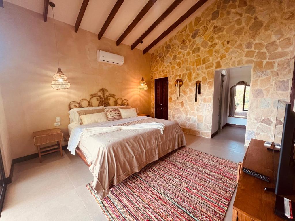 a bedroom with a large bed in a stone wall at Tinamaste in Uvita