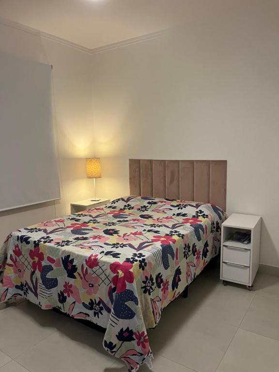1 dormitorio con 1 cama con colcha de flores en Casa 331 en Jaguariúna
