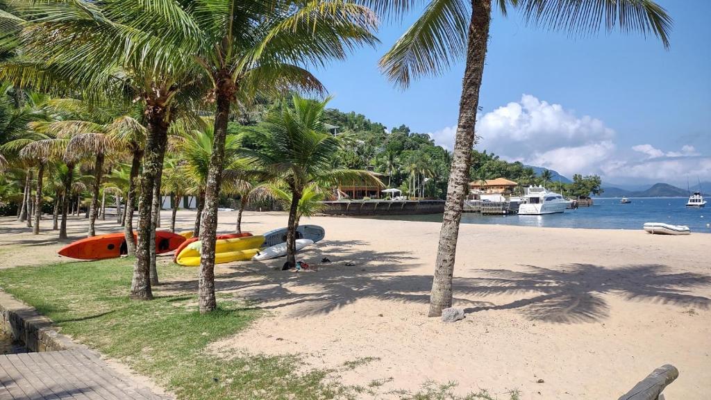 a beach with palm trees and a boat on it at Portogalo suíte com SPA in Angra dos Reis