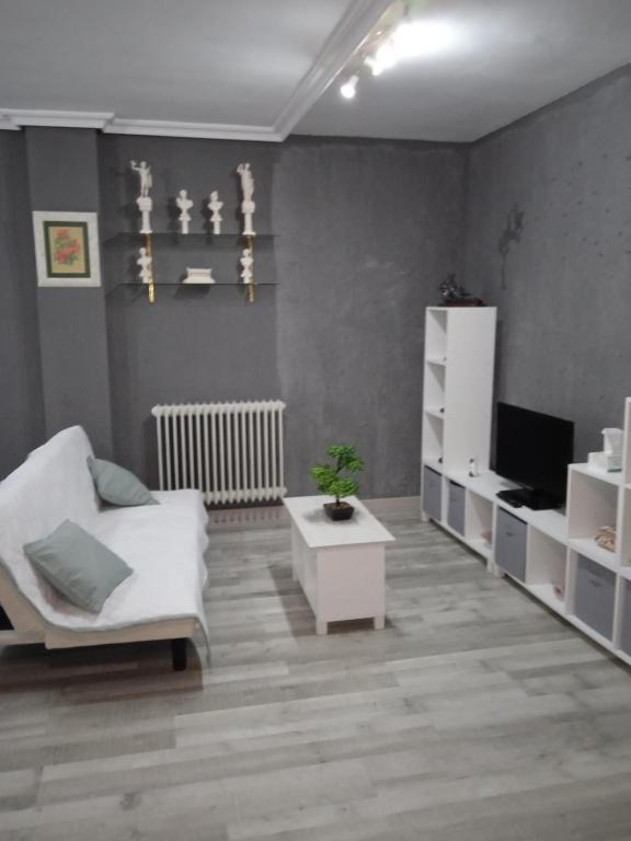 a living room with a white chair and a tv at Apartamento Roma in Ciudad-Rodrigo