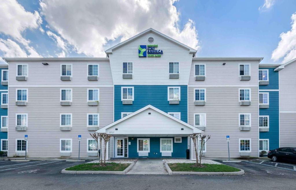 un gran edificio blanco y azul con aparcamiento en Extended Stay America Select Suites - Orlando - Sanford - Airport en Sanford