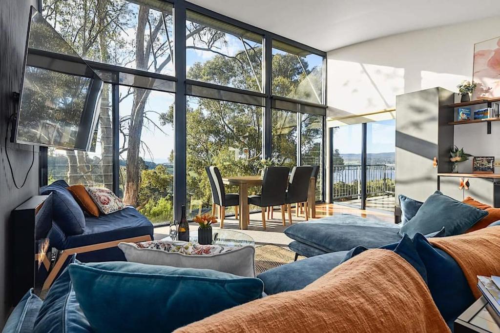 ein Wohnzimmer mit blauen Sofas und einem Tisch in der Unterkunft Tamar Valley Treetop Retreat in Grindelwald