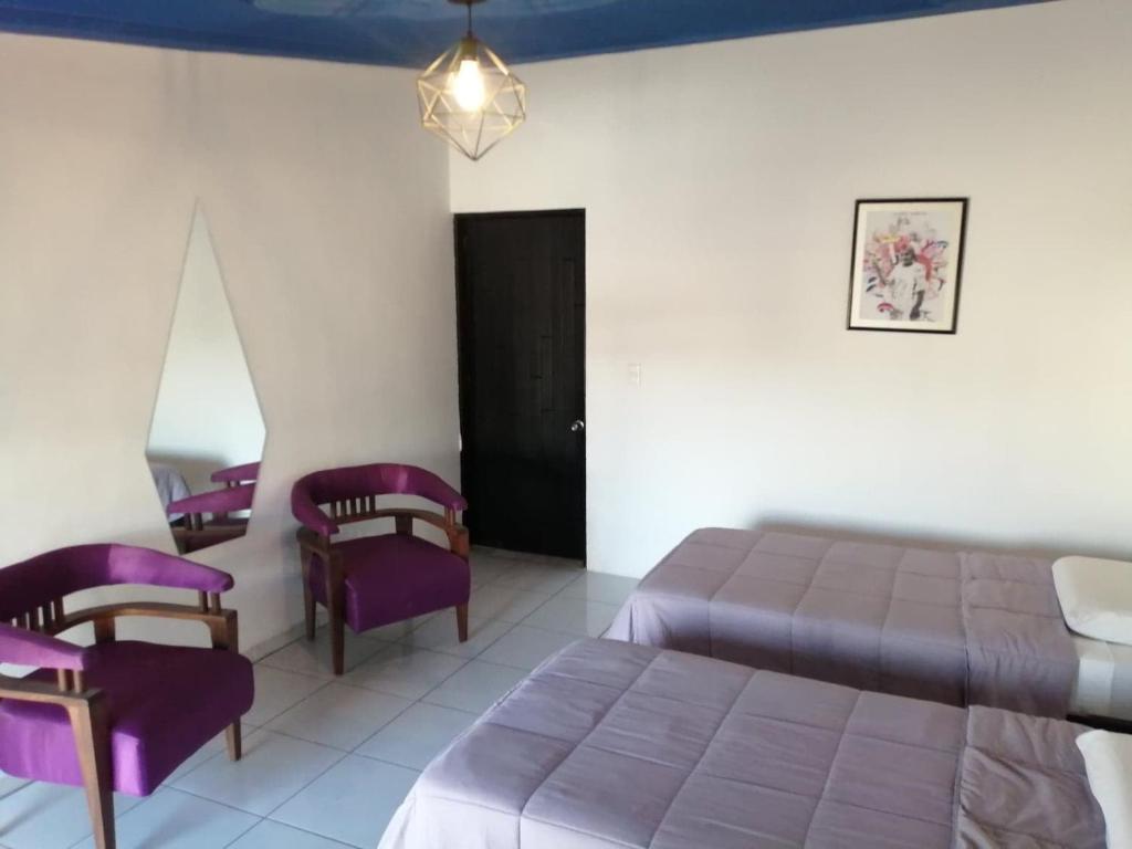 een slaapkamer met paarse bedden en paarse stoelen bij Hostal Casa Violeta in Tepic
