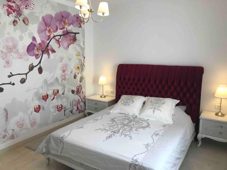 een slaapkamer met een bed met een bloemenmuur bij Charmant appartement à la Soukra in La Soukra