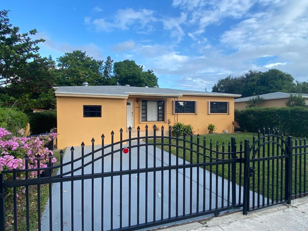 uma casa amarela atrás de uma cerca preta em Entire private Studio apartment em North Miami Beach
