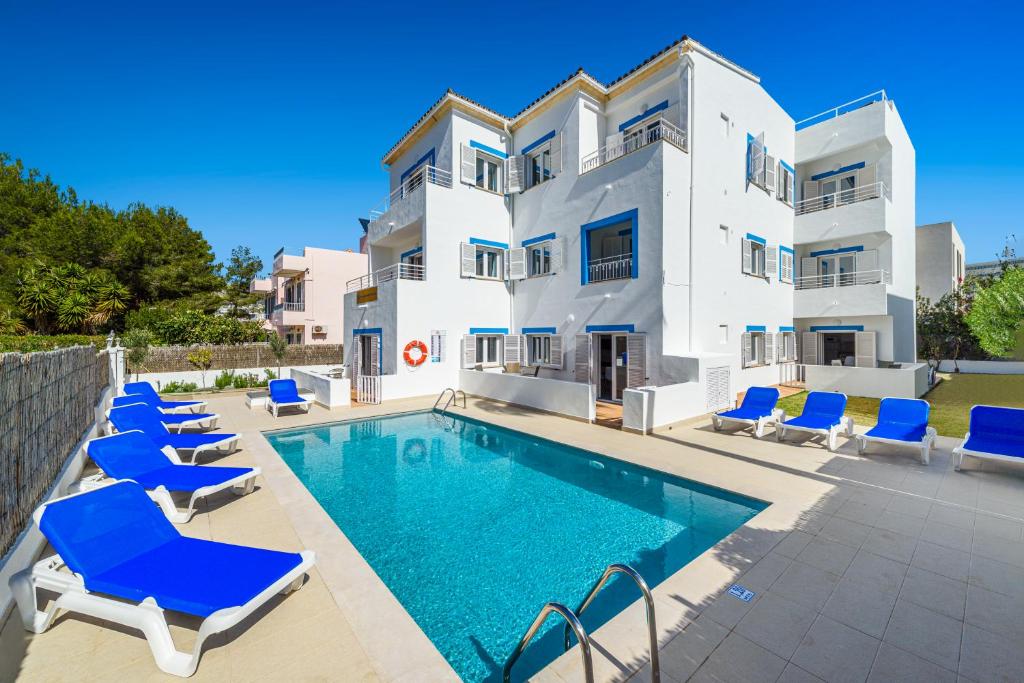 a villa with a swimming pool and blue lounge chairs at Apartamentos Falcó in Port de Pollensa