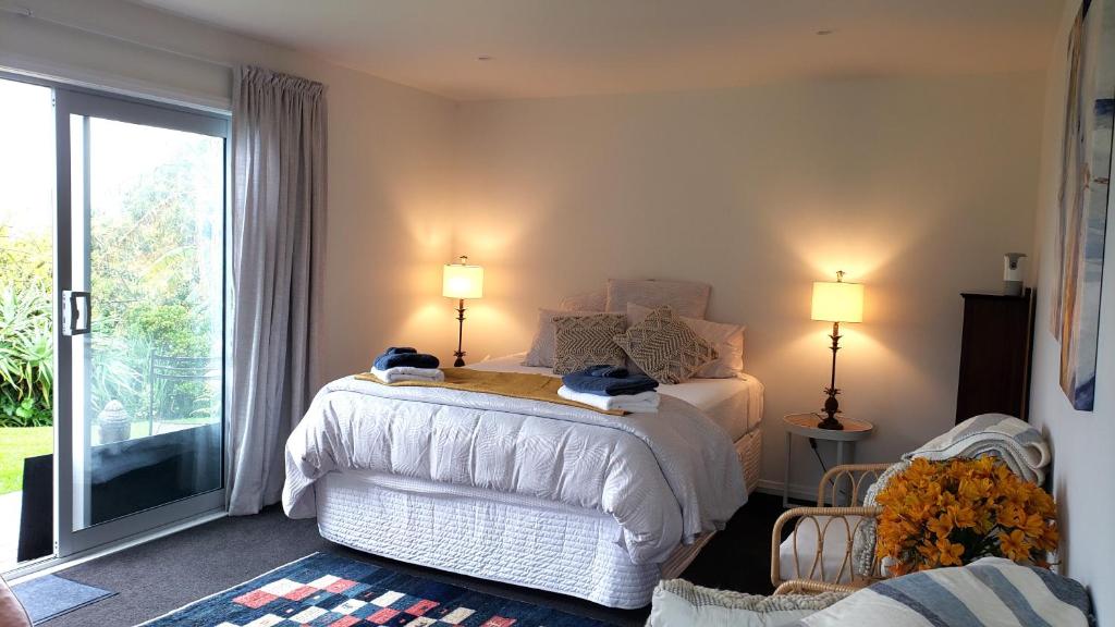 a bedroom with a white bed and a large window at seaview in Tairua