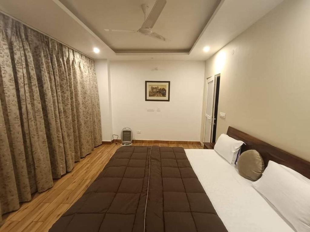 a bedroom with a large bed and curtains at Sun Rise View at Twin Oaks' in Kasauli