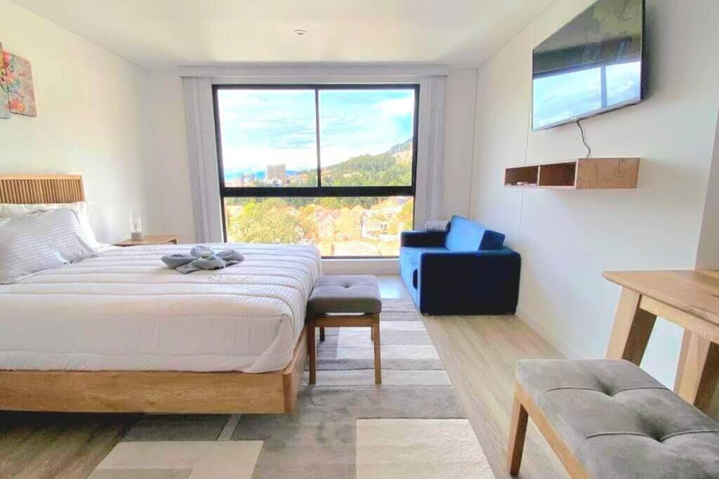 um quarto com uma cama, uma cadeira e uma janela em Loft en Centro Internacional con Vista Increíble em Bogotá
