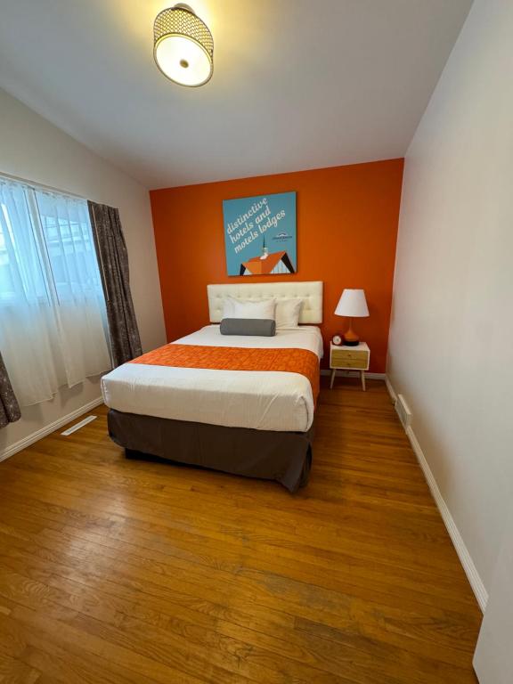 a bedroom with orange walls and a large bed at Hojo House Winnipeg in Winnipeg