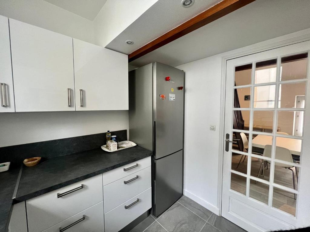 a kitchen with white cabinets and a refrigerator at Le 46 Magenta - Grand Duplex en hypercentre in Poitiers