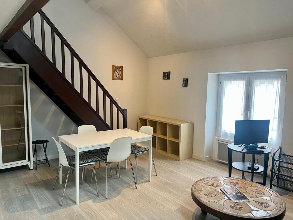 a living room with a table and chairs and a staircase at Le 46 Magenta - Grand Duplex en hypercentre in Poitiers