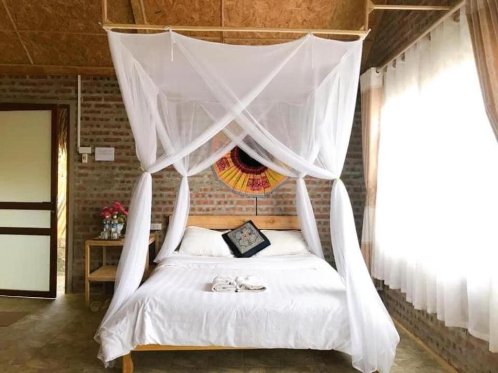 Un dormitorio con una cama blanca con dosel. en Eco Homestay Mai Chau - Venuestay, en Mai Chau