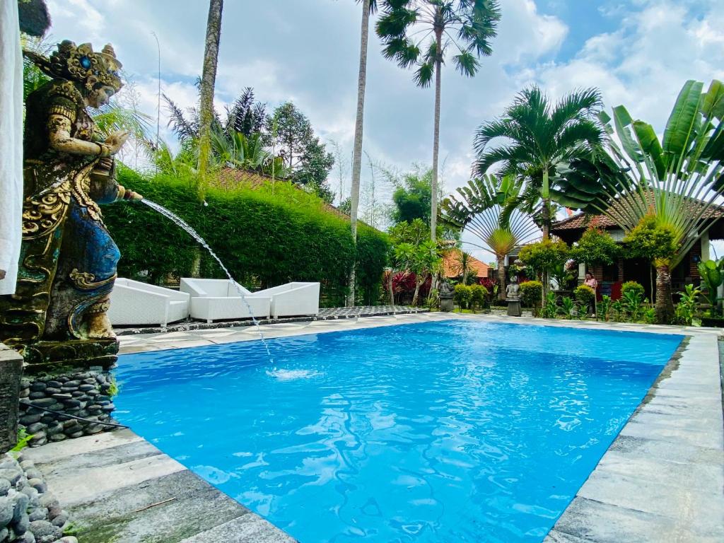a pool with a water fountain in front of a house at Dong Loka Guesthouse Bali in Payangan