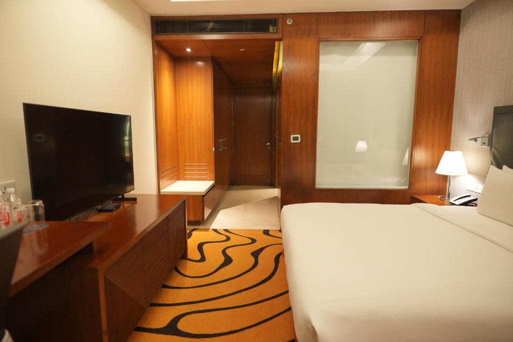 a bedroom with a bed and a flat screen tv at DoubleTree by Hilton Gurgaon New Delhi NCR in Gurgaon