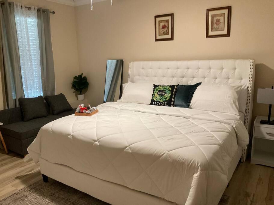 ein Schlafzimmer mit einem großen weißen Bett und einer Couch in der Unterkunft Stylishly designed basement. in Lawrenceville