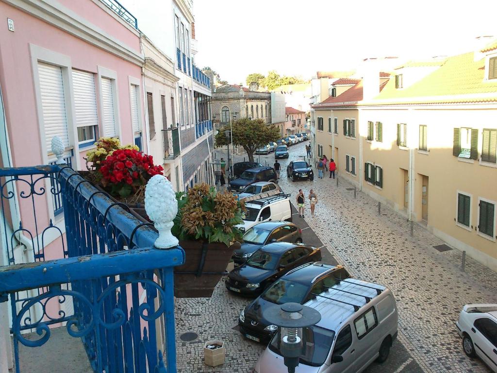 rząd samochodów zaparkowanych na ulicy obok budynków w obiekcie Andar com jardim e estacionamento w mieście Paço de Arcos