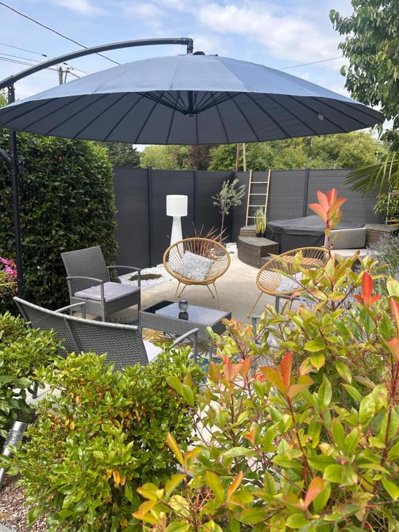 a patio with chairs and an umbrella in a garden at Gîte le bas ray près de Beauval in Veuil