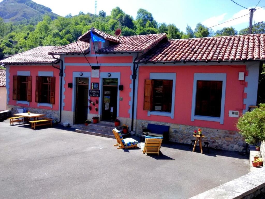 un edificio rojo con sillas delante en Alojamiento covadonga en La Riera