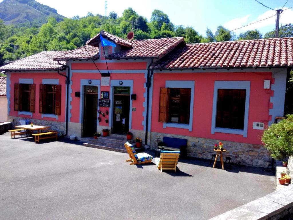 a red building with chairs in front of it at Alojamiento covadonga in La Riera