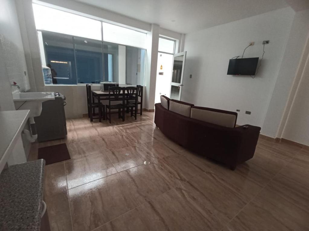 a living room with a couch and a table and chairs at CARDOS HOSTAL in Pisco