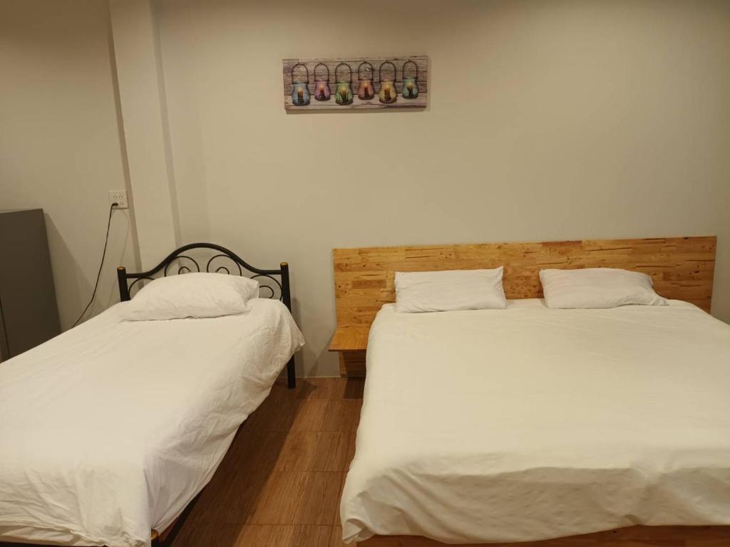 dos camas sentadas una al lado de la otra en una habitación en โรงแรมควีนส์ (Queen) en Ban Tha Kham