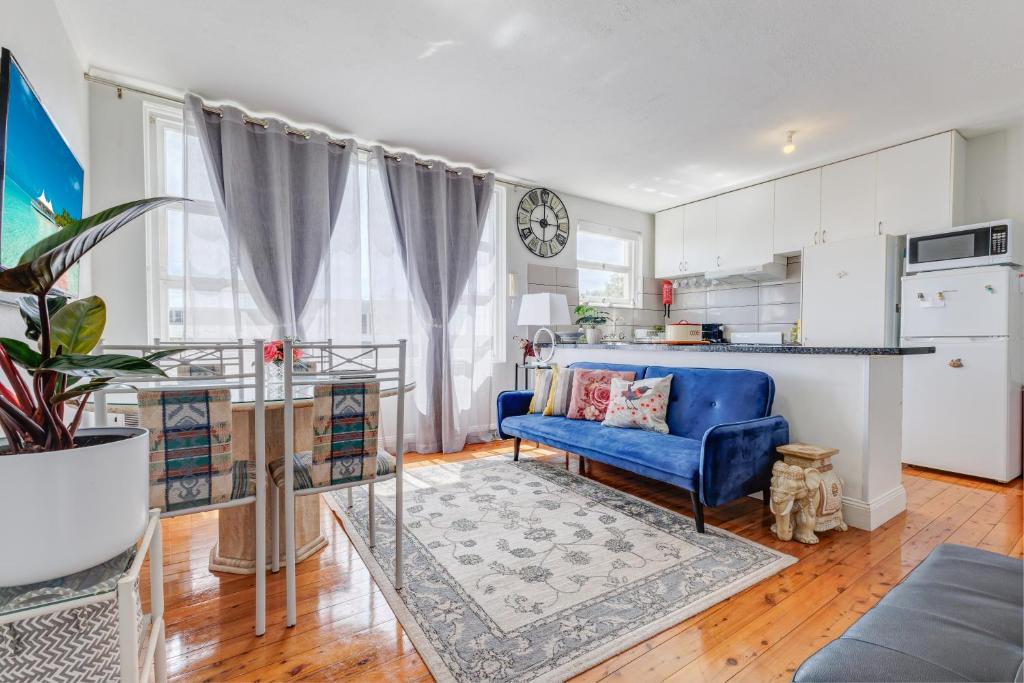 a living room with a blue couch and a kitchen at Miracle Miranda Sydney Apartment in Miranda