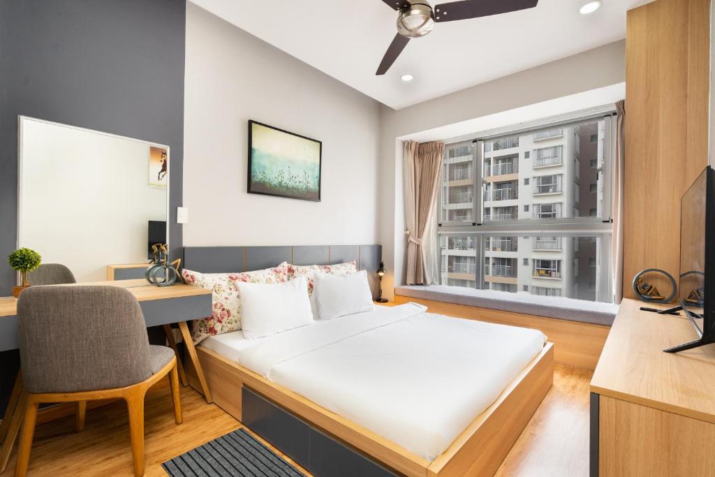 a bedroom with a bed and a desk and a window at Lena Condotel in Ho Chi Minh City