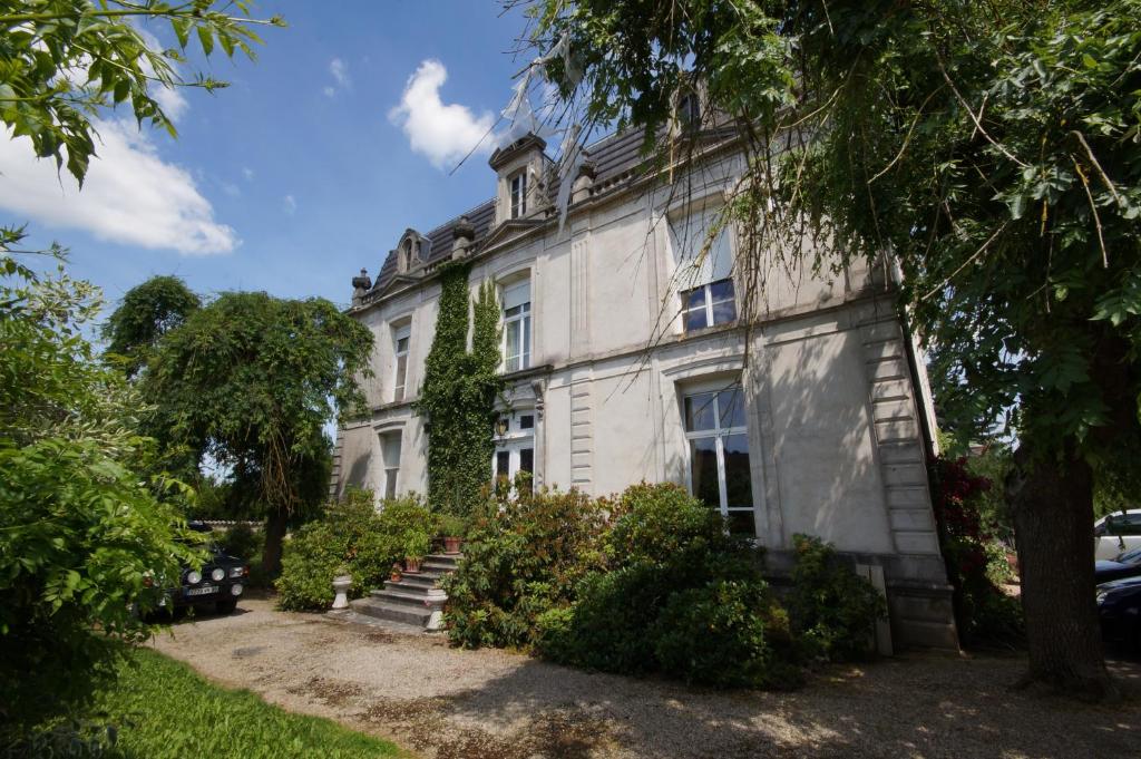 un grand bâtiment blanc avec des arbres devant lui dans l'établissement Le Clos Domremy, à Domrémy-la-Pucelle